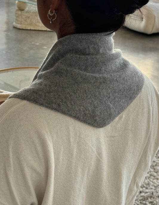 Person wearing a gray scarf around their neck with a blurred background