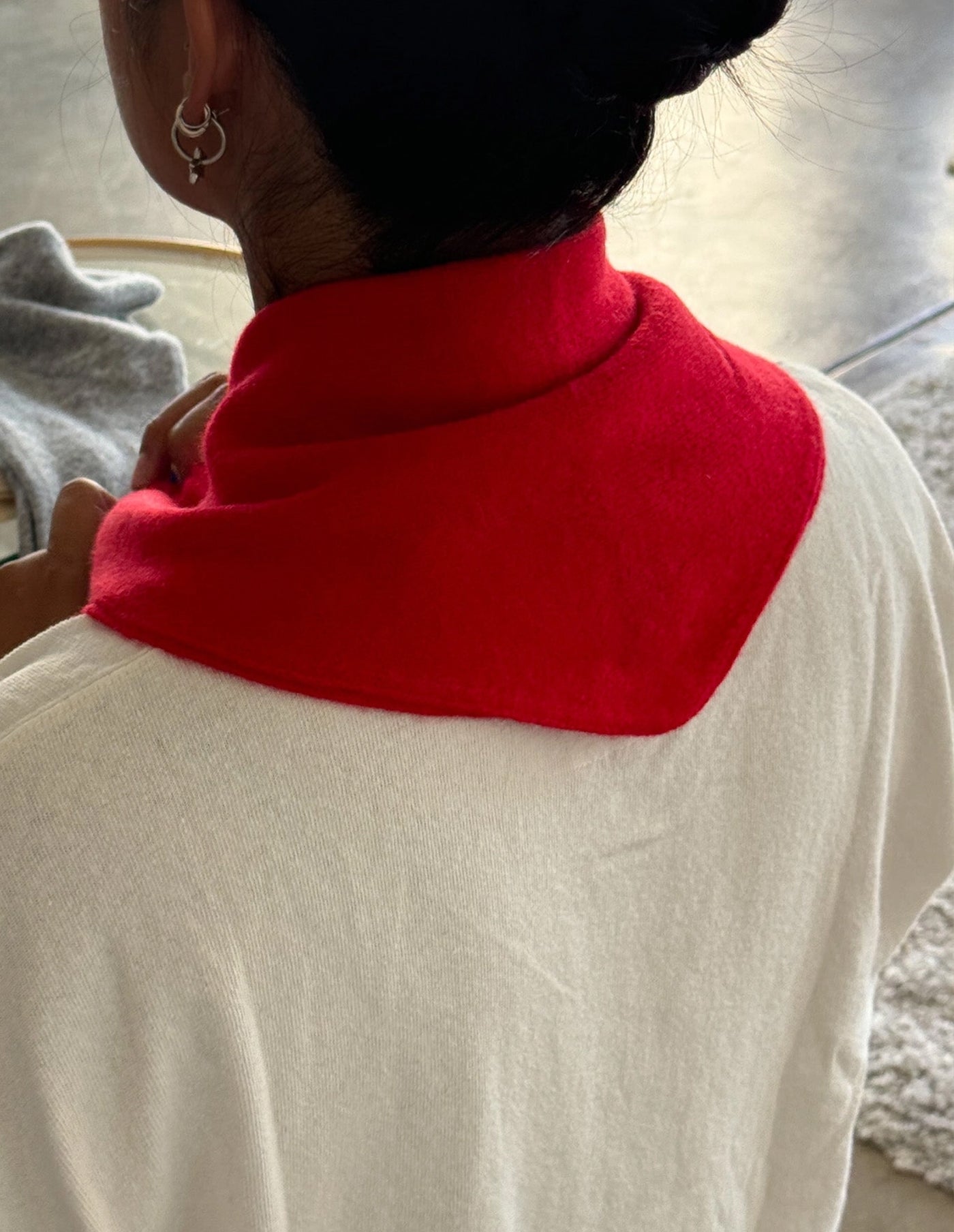 Person wearing a red scarf around their neck with a neutral background