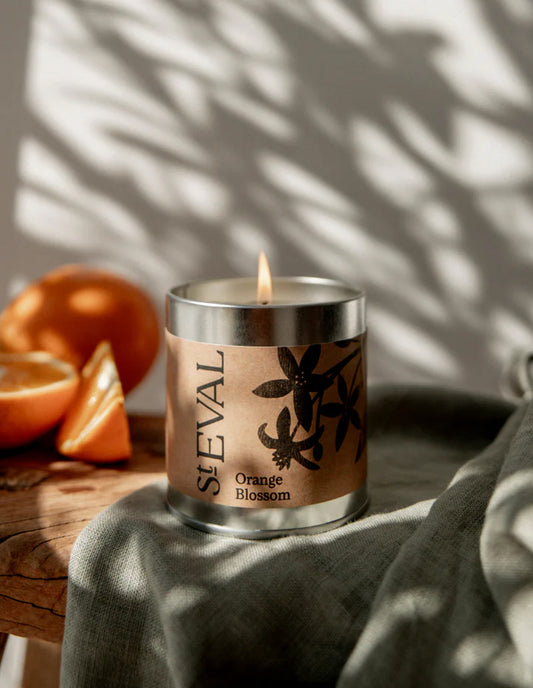 Sleval Orange Blossom candle on a wooden surface with oranges and a plant in the background