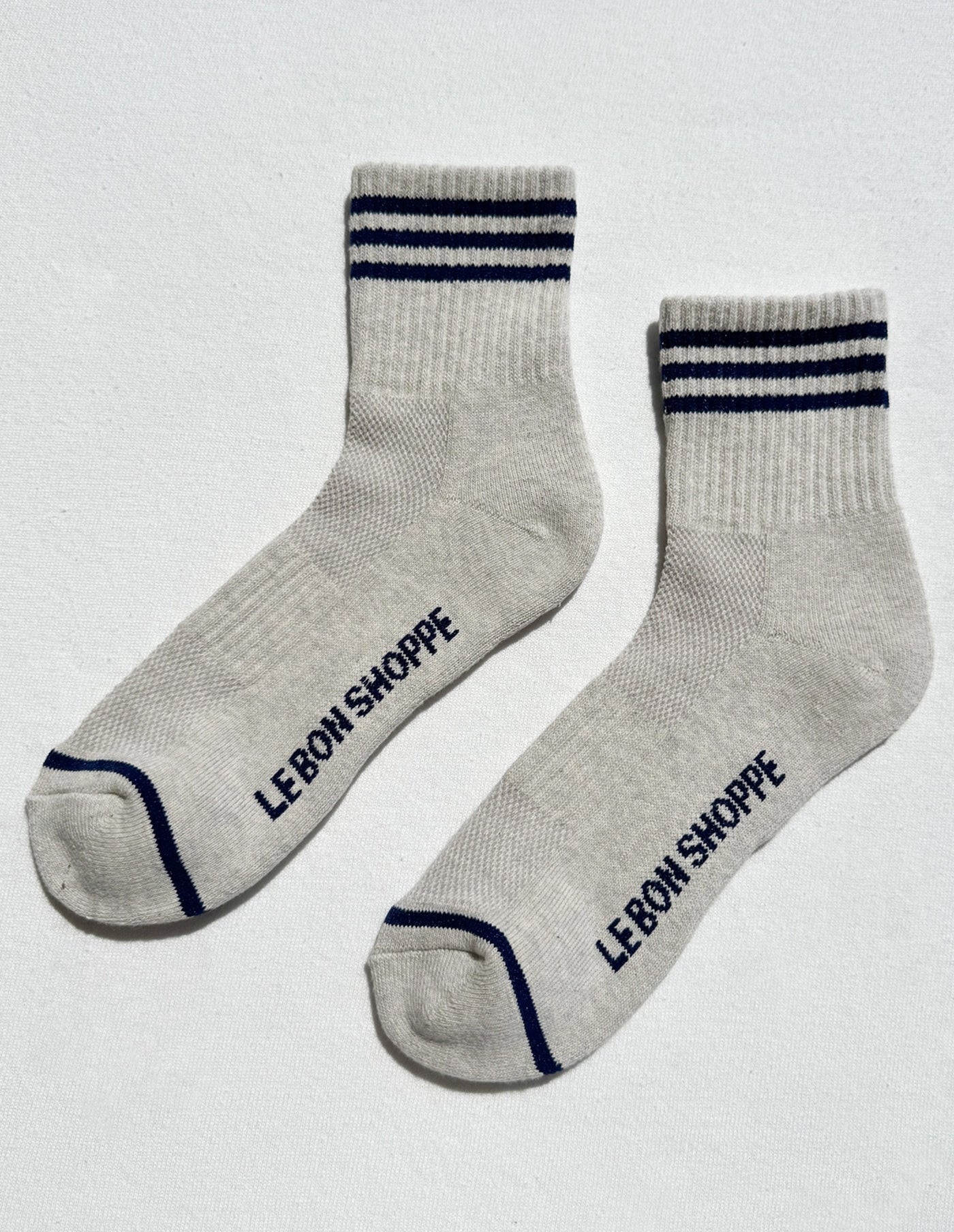 Gray socks with blue stripes and 'Le Bon Shoppe' branding on a light gray background