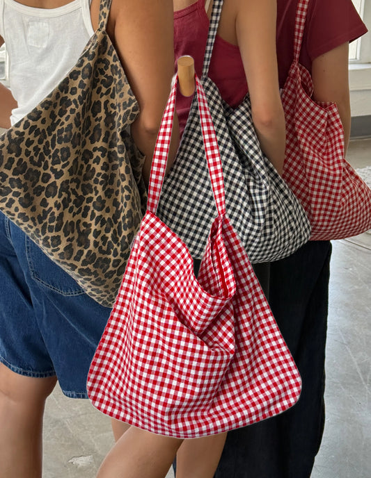 Three people holding patterned bags: leopard print, red and white checkered, and black and white checkered.