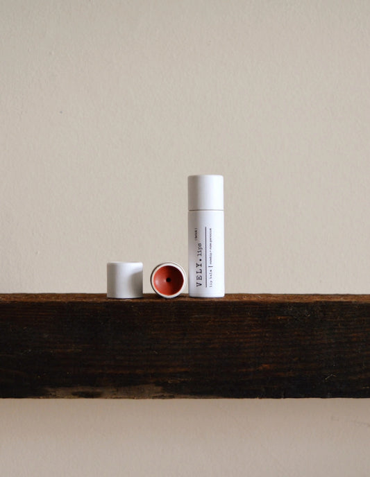 Three cylindrical containers with different colored caps on a wooden surface against a beige wall.