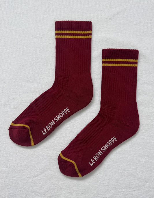 Maroon socks with gold stripes and 'Lebon Shoppe' branding on a light gray background