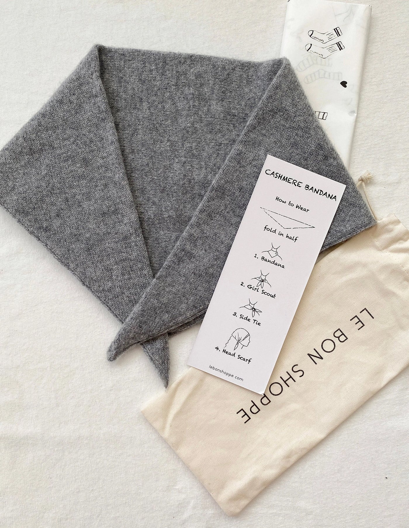 Gray cashmere bandana with a label and storage bag on a light background
