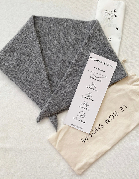 Gray cashmere bandana with a label and storage bag on a light background