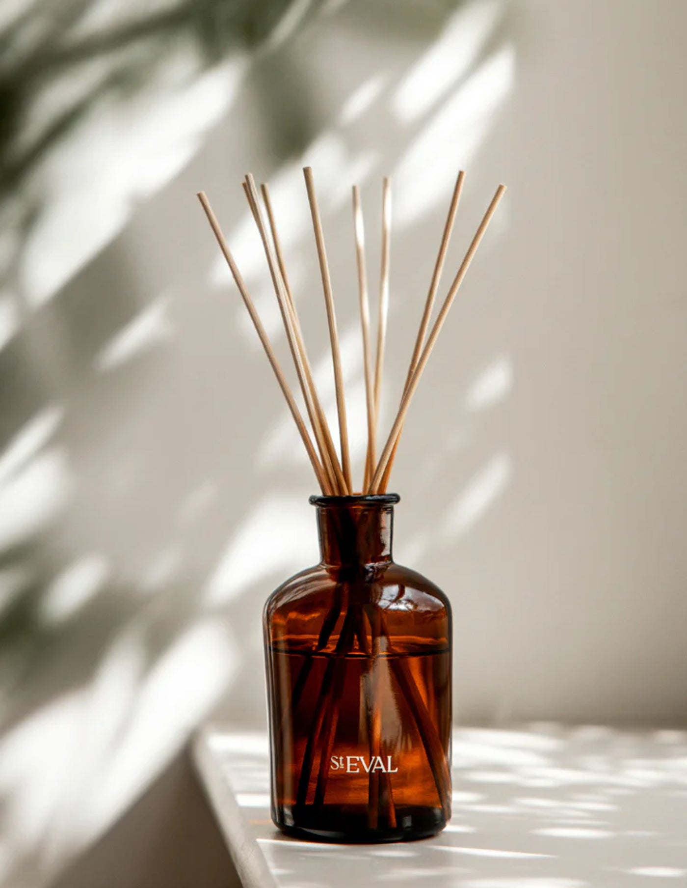 Brown diffuser bottle with wooden sticks on a light background