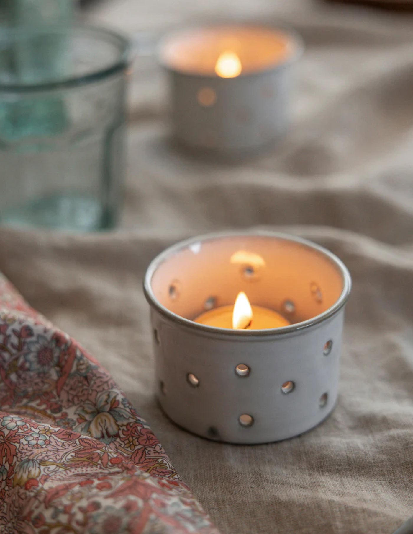 Candle in a decorative holder on a textured surface with a blurred background