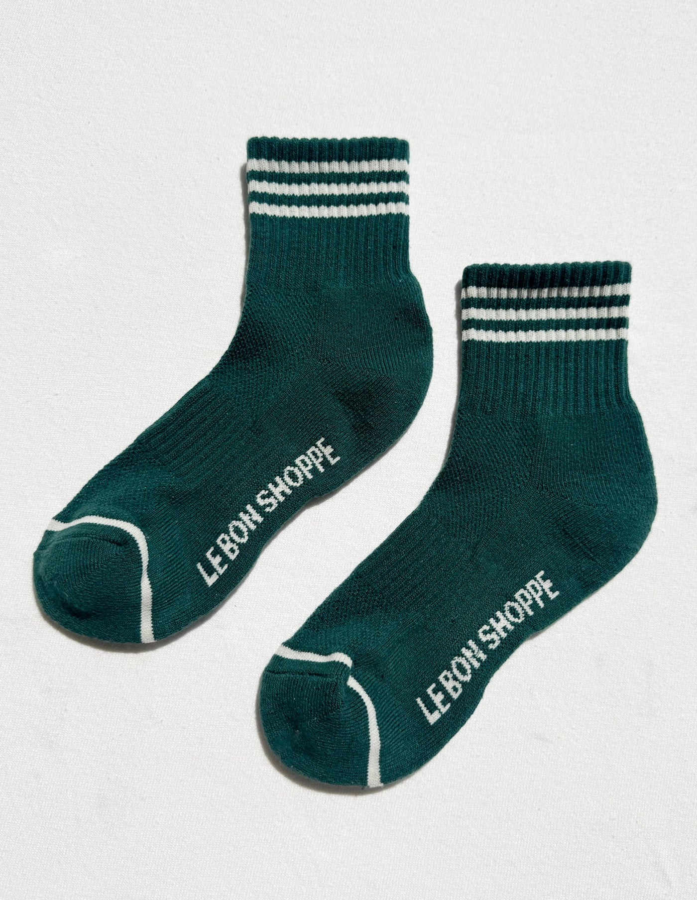 Green socks with white stripes and 'Le Bon Shoppe' branding on a light gray background
