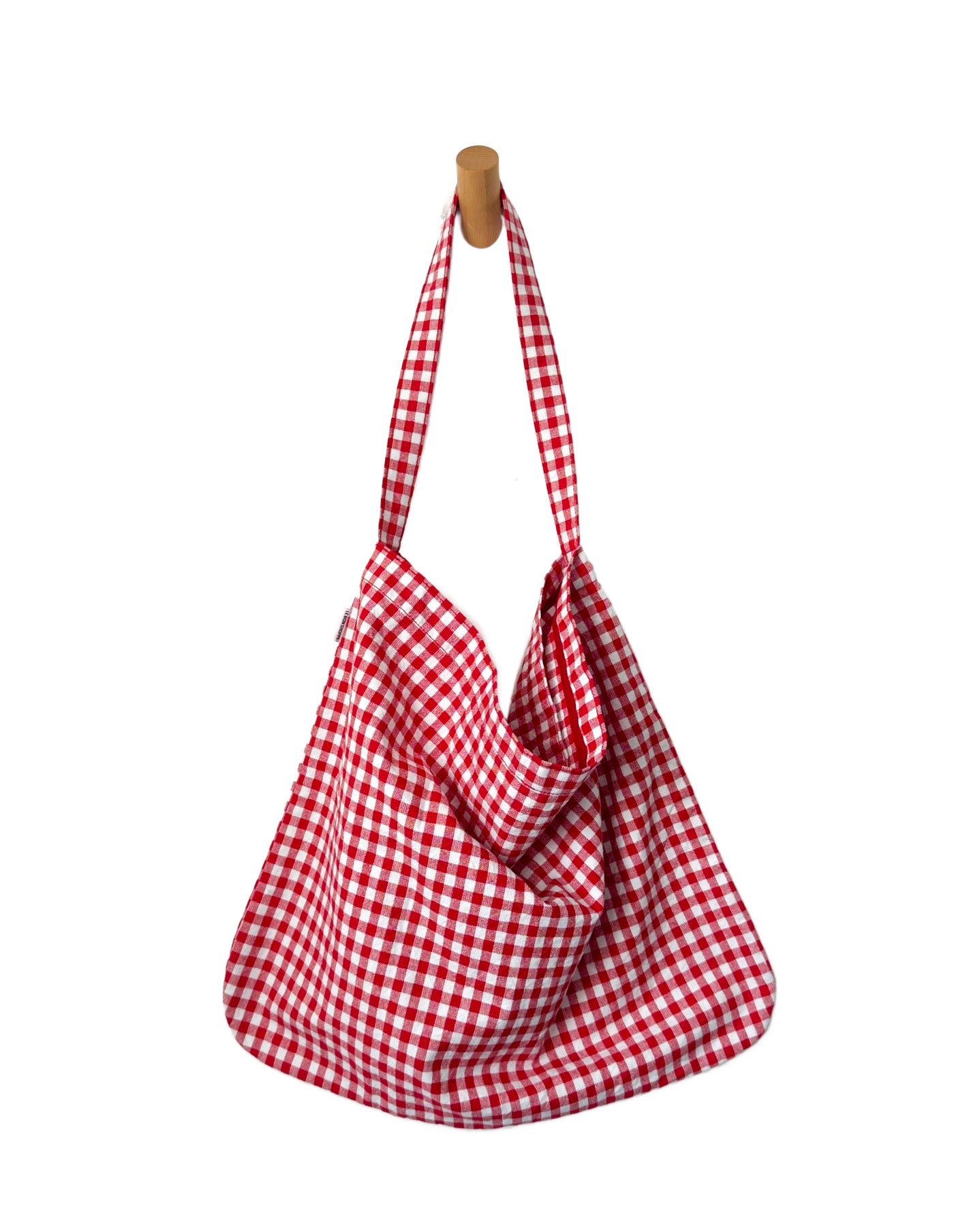 Red and white checkered bag hanging on a wooden hook against a white background