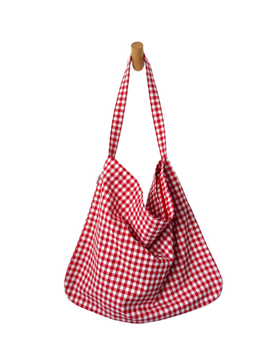 Red and white checkered bag hanging on a wooden hook against a white background