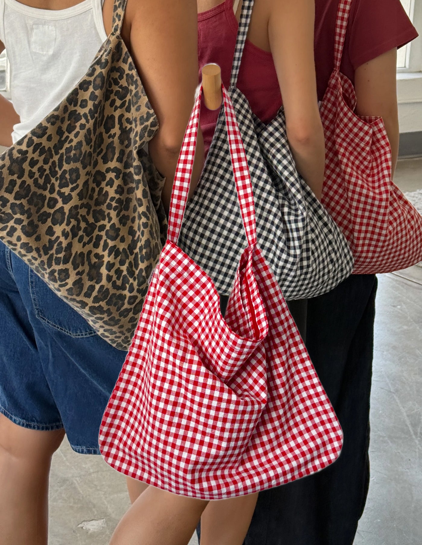 Three people holding patterned bags: leopard print, red and white checkered, and black and white checkered.