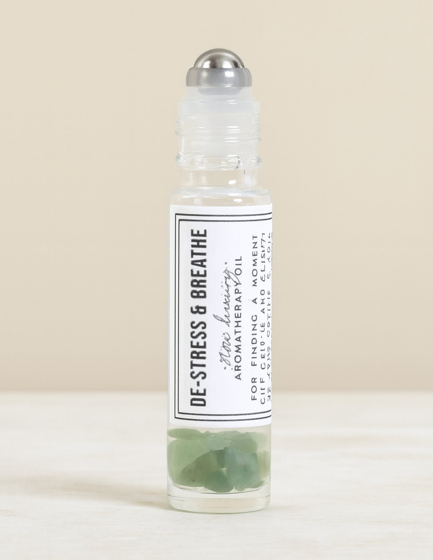 Roll-on bottle of 'De-Stress & Breathe' aromatherapy oil on a beige background