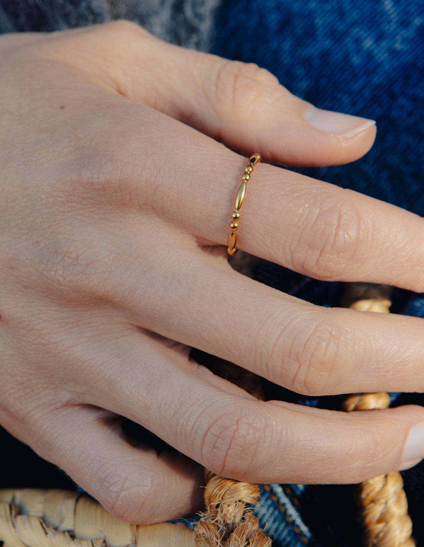 Close-up of a hand wearing a gold ring with a textured band.
