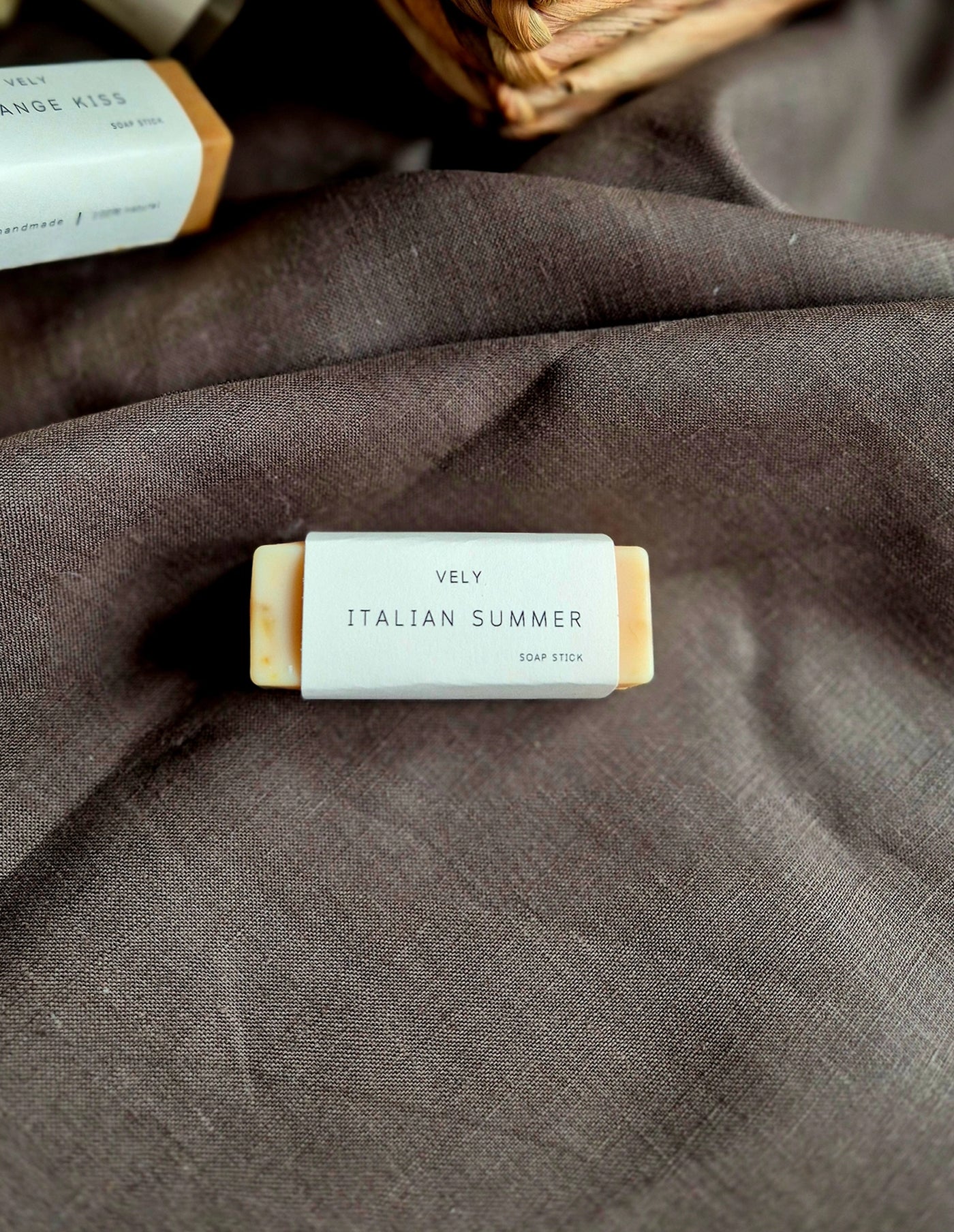 Bar of soap labeled 'Vely Italian Summer' on a textured brown fabric background