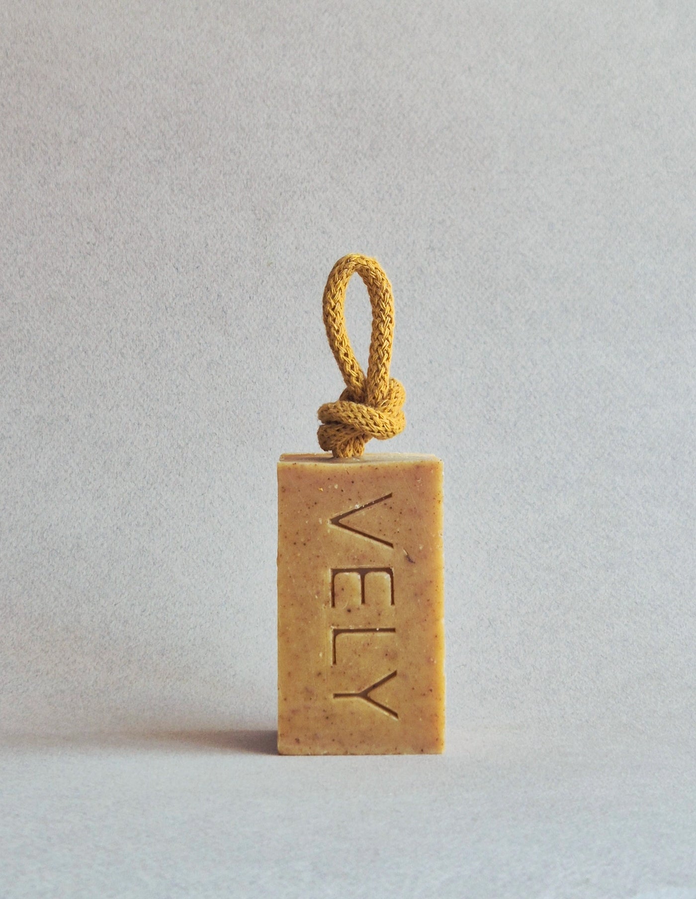 Rectangular bar of soap with a rope on a light gray background