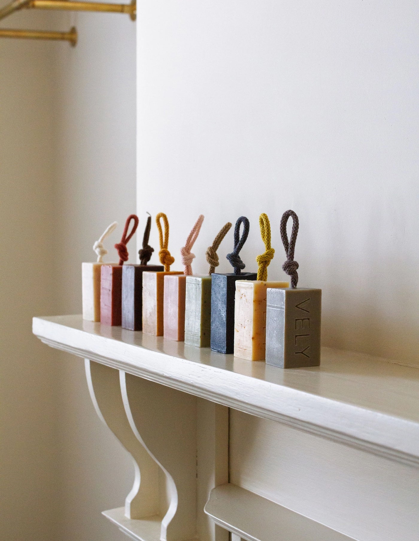 Set of colorful bottle stoppers on a white shelf against a neutral wall.
